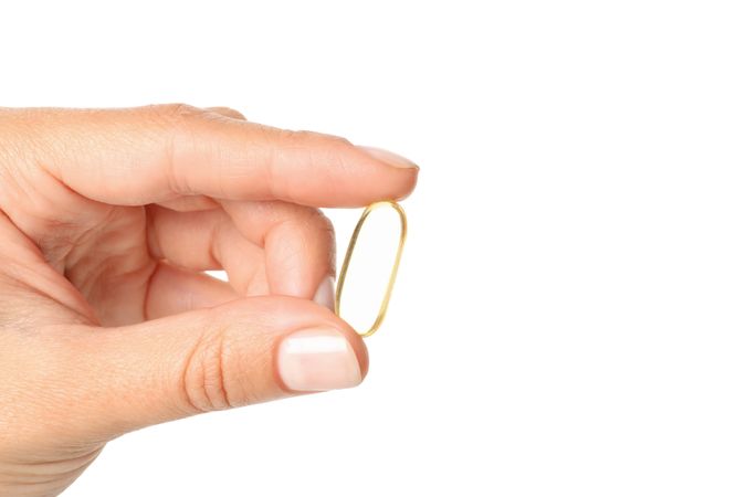 Omega pills in hand, isolated on blank background