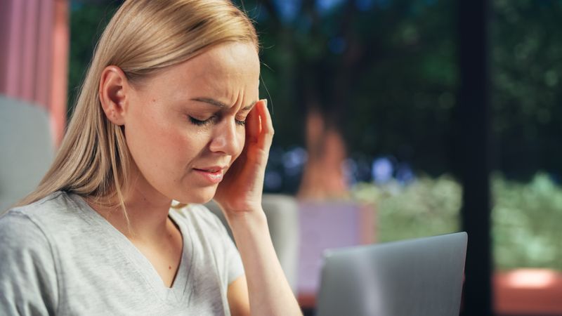 Human Going Through Headache: Close Up of a Female Working on Laptop Computer and Experiencing Discomfort and Migraine.