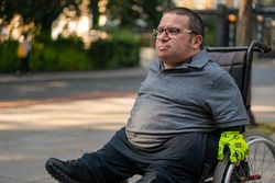 Portrait of man sitting in wheelchair on city sidewalk