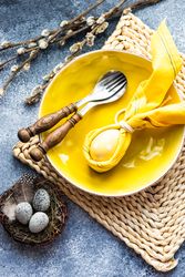 Easter holiday table setting with yellow egg decoration in bunny napkin on plate