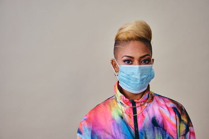 Studio shot of Black woman in vibrant 80s windbreaker jacket wearing a face mask