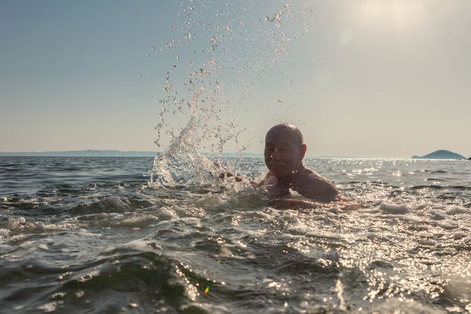 Active man swimming and splashing in water