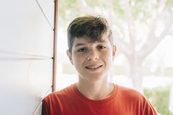 Portrait of a cheerful male teen outside in sunny yard