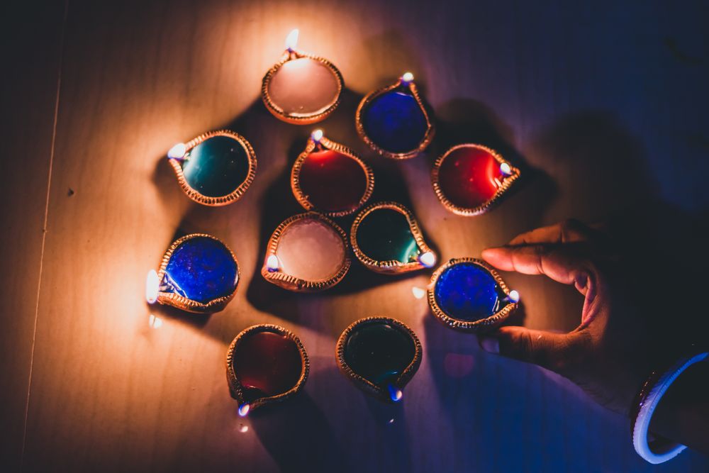 Top view of hand near colorful lit diyas