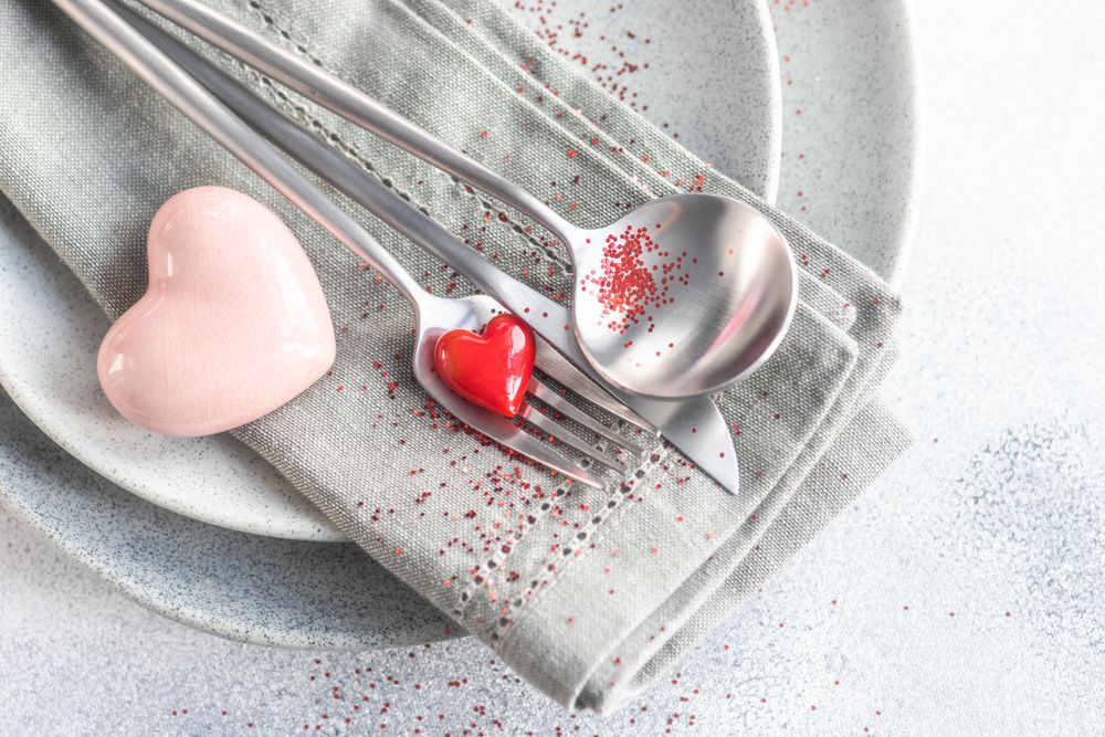 Valentine Day holiday card concept with red glitter and hearts adorning grey plates
