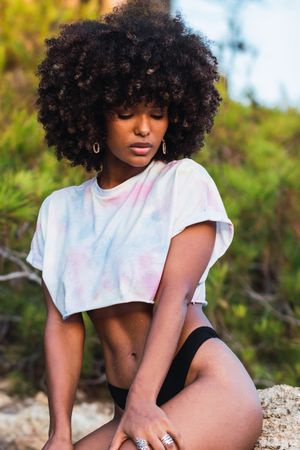 Slim Black woman in crop top and bikini on beach