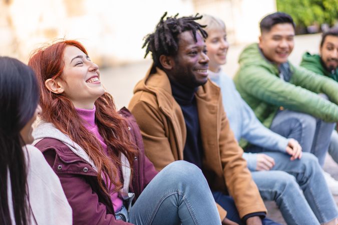 Laughing red-haired woman with diverse friends enjoying a casual outdoor meeting
