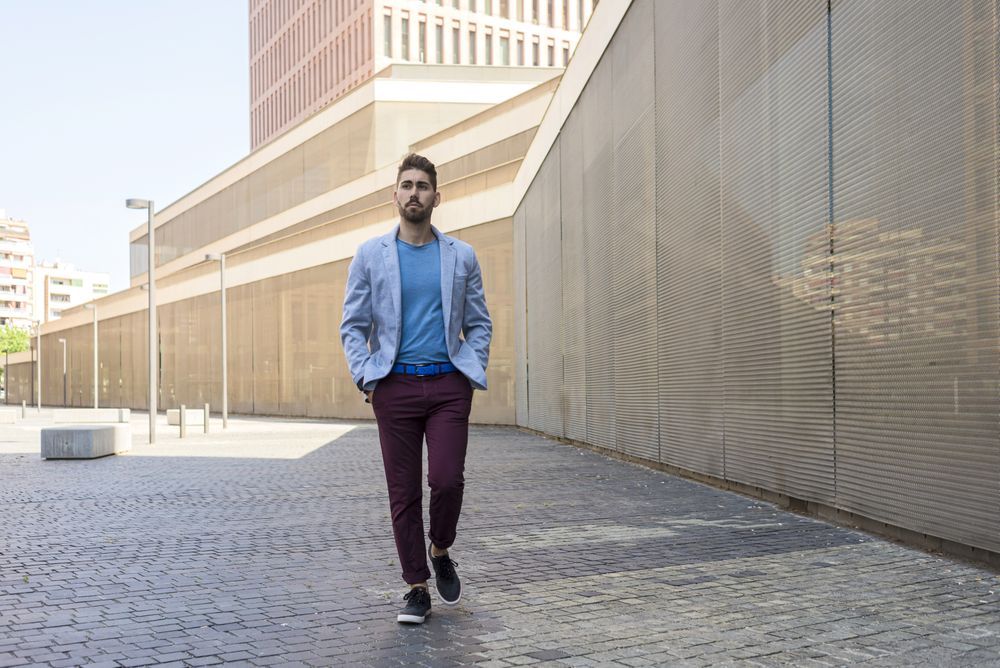 Man in blazer walking on street with hands in pockets