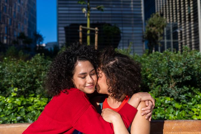 Female couple in love hugging in city park