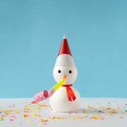Snowman on bright blue background with party hat and party blower