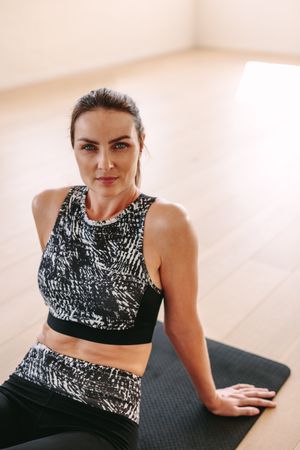 Close up of a woman sitting on fitness mat