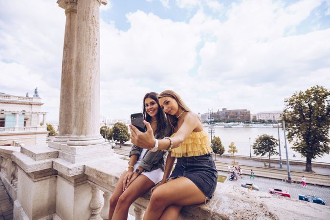 Laughing women taking selfie on old building