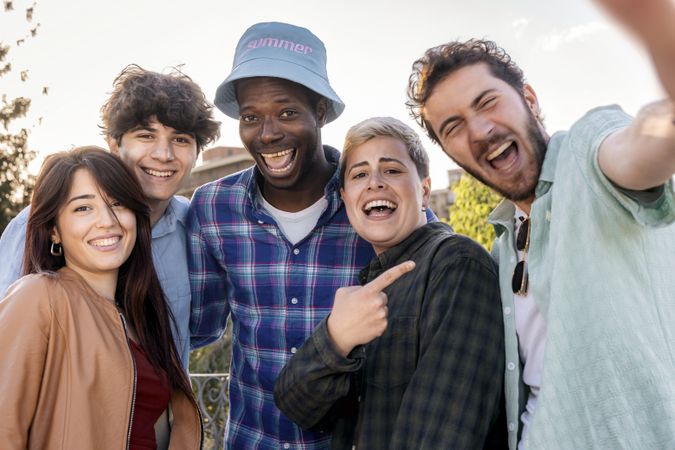 Happy diverse group of young friends taking a selfie outdoors during summer day in the city