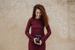 Cheerful woman with camera near rough wall