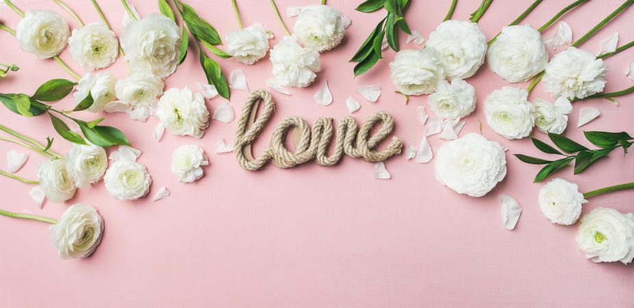 “Love” written in jute against pink background with flowers, copy space