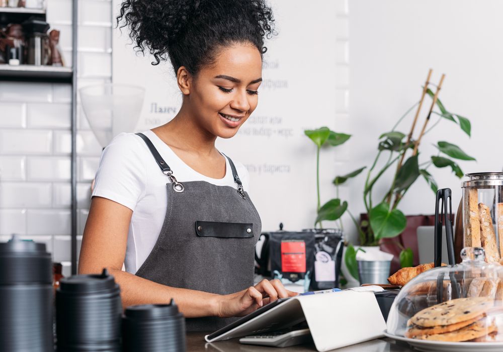 Barista working on digital tablet in cafe