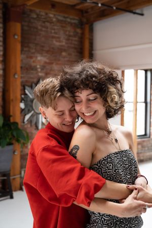 Happy young couple smile and look down while sharing an embrace