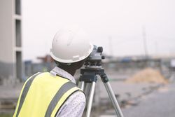 Back view of man with bump hat looking through a telescope