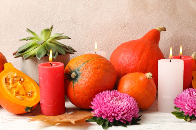 Composition with pumpkins, flowers and candles on wooden  background, copy space