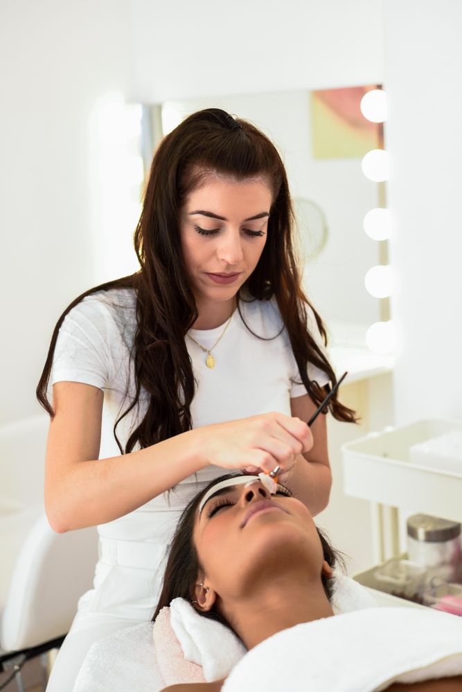 Woman having eye brow treatment in beauty salon, vertical