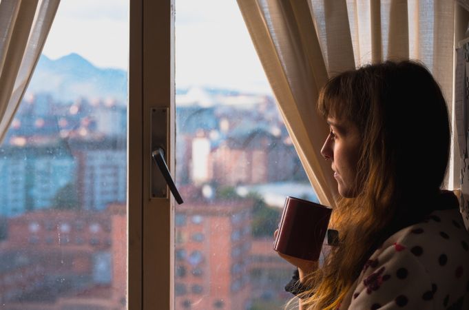 Woman enjoying hot beverage near fridge