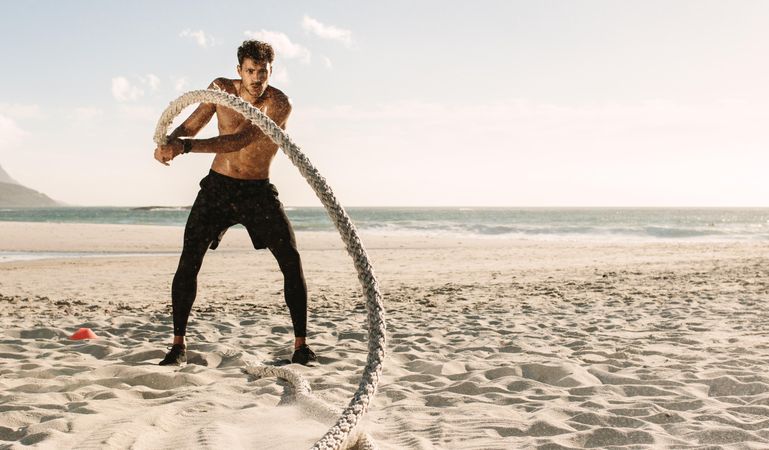 Lean man doing fitness workout at a beach on a summer day