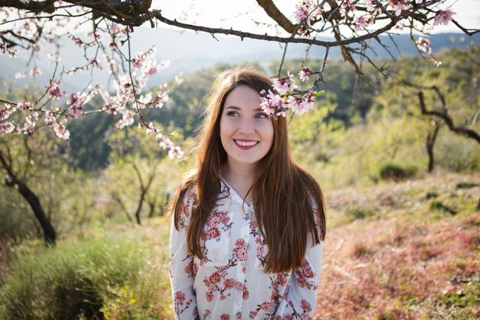 Young happy woman between trees in garden