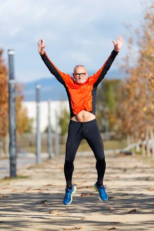 Fit older male doing a star jump during workout