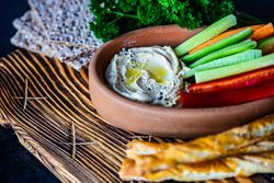 Hummus dish served with chopped veggies and breadsticks