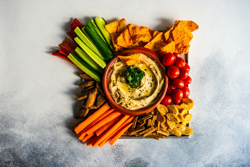 Top view of hummus dish with veggies on kitchen counter