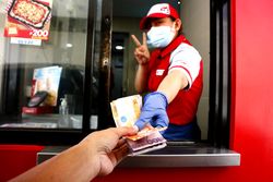 Fast food restaurant worker with facemask serving a customer at a drive thru facility 4A9pW4