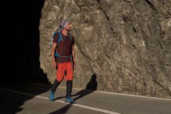 Traveling man walking on asphalt road near mountains