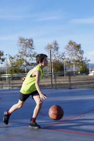Teenager dribbling basketball on an outdoors court