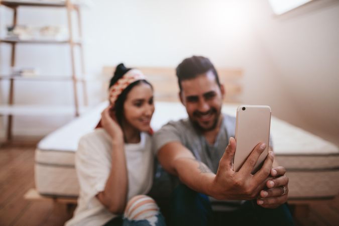 Close up of man holding mobile phone to take selfie with girlfriend
