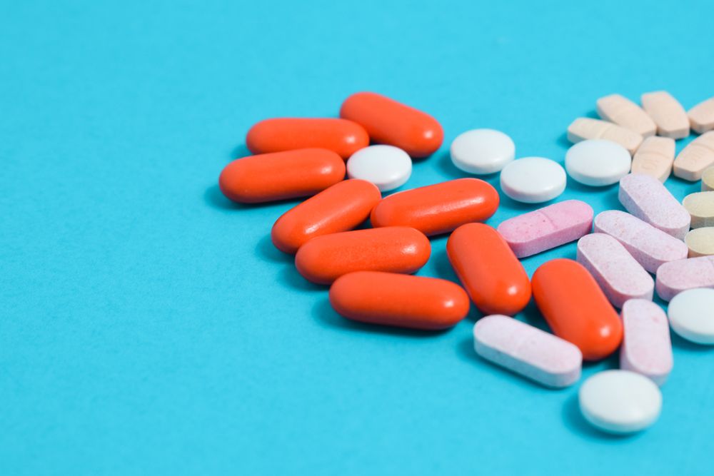 Mix of pIlls in heart shape on blue background