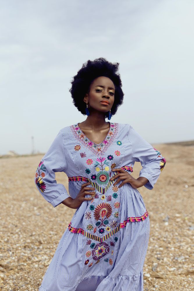 Woman in light dress with floral embroidery posing outdoor