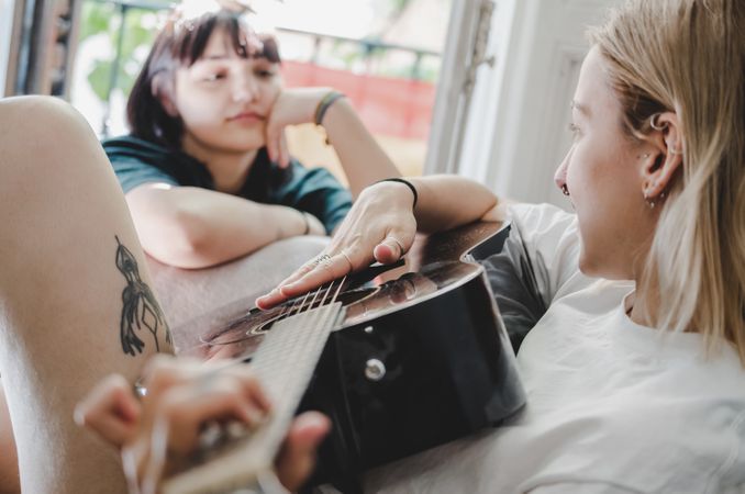 Lesbian couple playing guitar on bed
