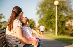 Baby girl and woman sitting on a park bench