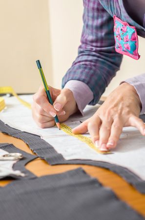 Dressmaker drawing tailor pattern on the table