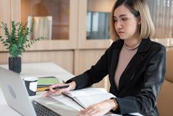 Asian female manager working on project using laptop
