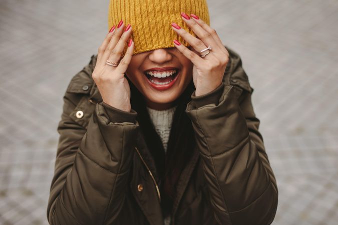 Laughing woman covering eyes with knit cap