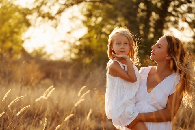 Woman holding little girl in marsh at sunset