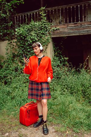Woman in headphones with suitcase choosing music