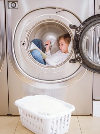 Concentrated boy reading book in laundry room