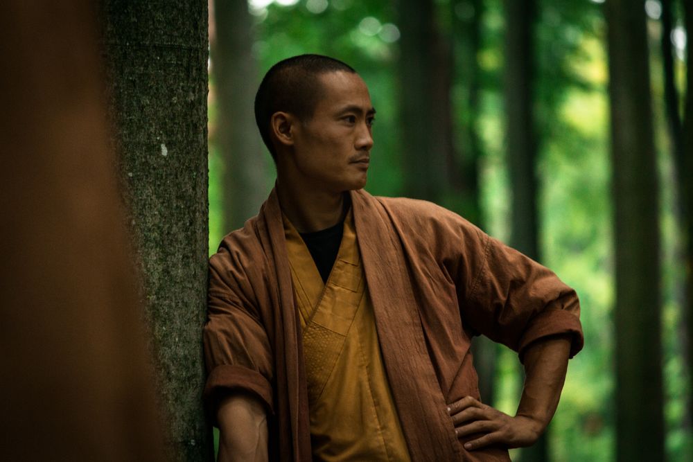 Asian guy in brown uniform resting in green forest