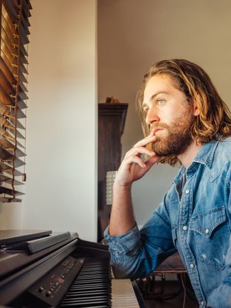 Thoughtful male playing synthesizer at home
