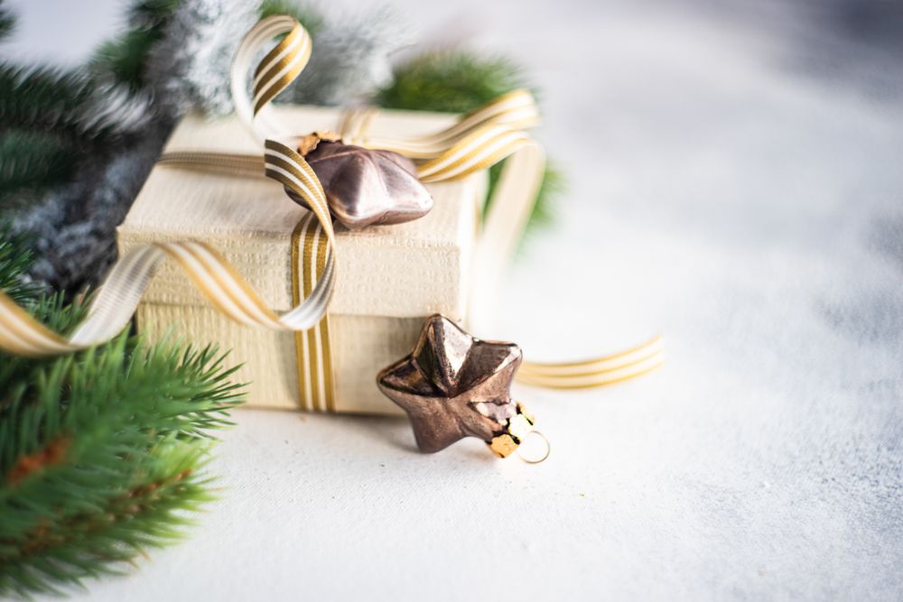 Christmas present with gold ribbon and star decorations on marble counter