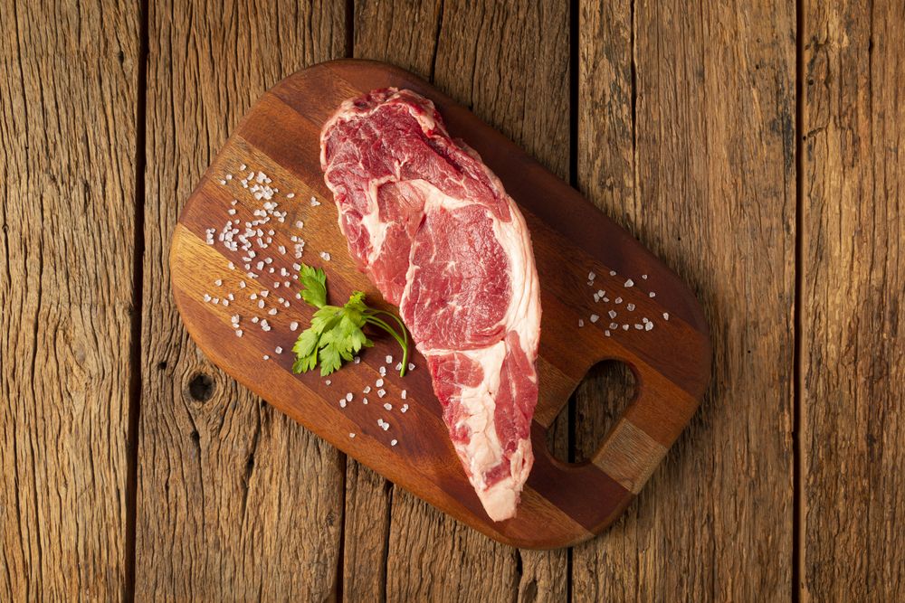 Raw ancho meat ready to roast on a wooden cutting board.