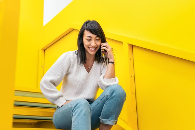 Smiling Asian woman talking on the phone in a coworking