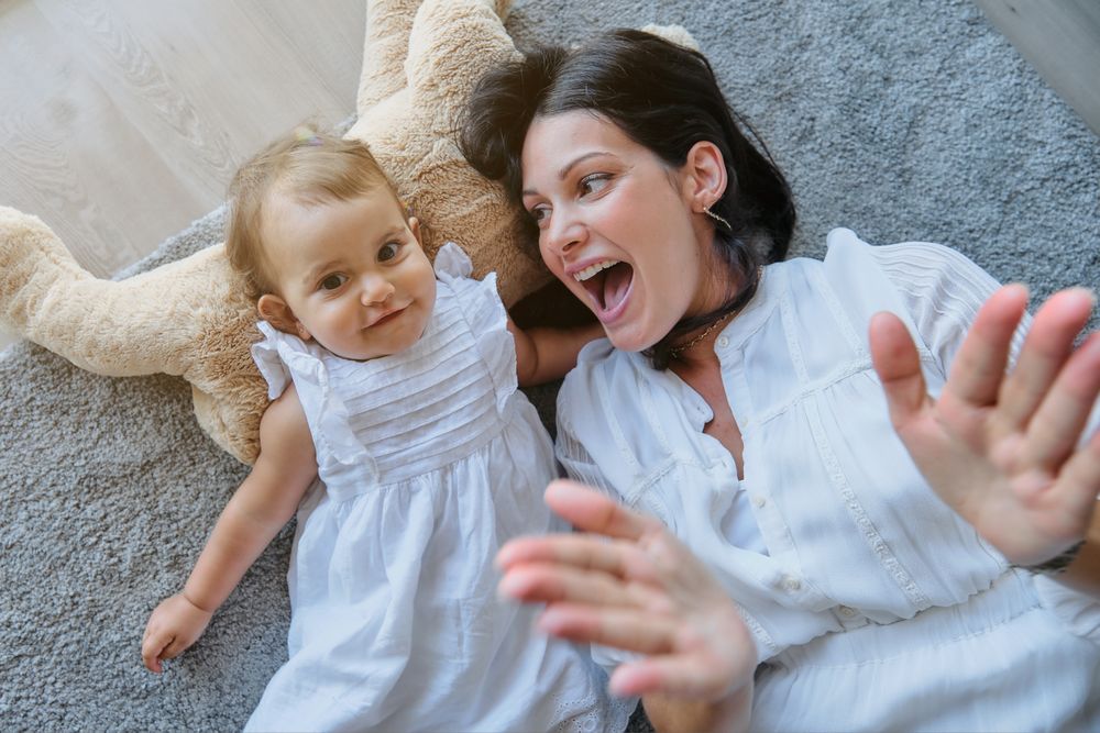Cheerful mother and daughter lying on carpet